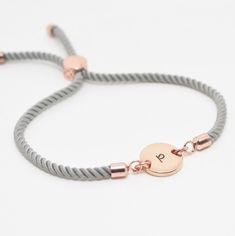 Step into the wonderful world of personalized jewelry with our amazing Initial bracelet on grey cord!  This special handmade bracelet is a delightful mix of a 12mm hand-stamped disc and an adjustable grey cord slider bracelet, making it a unique custom bracelet that's perfect for any occasion. ☆ Product Details: * Made from : Nylon cord in a beautiful grey colour. * Clasp: Slider clasp, allowing for easy and adjustable fitting to most wrist sizes. * Initial Disc : Choose from gold plated, rose g Customized Adjustable Rose Gold Name Bracelet, Minimalist Rose Gold Bracelet With Initials, Minimalist Rose Gold Initials Name Bracelet, Personalized Rose Gold Bracelet, 14k Gold Filled, Adjustable Rose Gold Bracelet With Initials, Initial Bracelet Gold, Rose Gold Initial, Gold Bracelet For Women, Rose Gold Bracelet