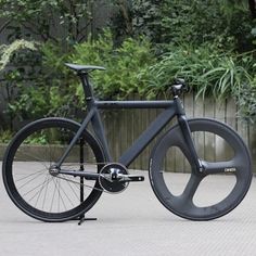 a black bicycle parked in front of a wooden fence