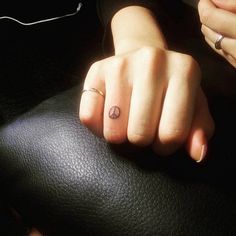 a person with a small tattoo on their left hand holding onto a black leather chair