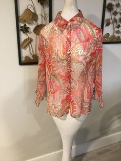 "Pretty chiffon top in shades of pink...abstract swirl and floral pattern.  Buttons up the front and the sleeve hems are ruffled.  Blouse is in nice condition, just washed and is ready to wear.  Label reads size L but please see measurements below to ensure a good fit.    Measurements: 44\" bust;  42\" mid body; 49\" hemline with slits on sides; 25 1/2\" tall; 18\" sleeve length. Thanks for stopping by my Etsy store!" Silk Pink Floral Print Blouse, Pink Chiffon Top, Pink Semi-stitched Floral Print Blouse Piece, Pink Floral Print Button-up Blouse, Vintage Multicolor Abstract Print Blouse, Sheer Floral Top, Non-stretch Multicolor Floral Print Blouse, Ruffled Blouse, Velvet Coat