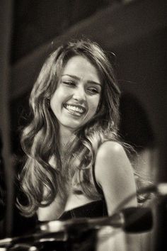 black and white photograph of a smiling woman in front of a piano with her eyes closed