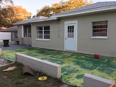 a house with green tarp covering the front yard and side of it, next to a fire hydrant