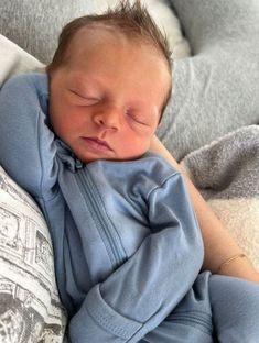 a baby sleeping on top of a pillow with his eyes closed and hands tucked under the head