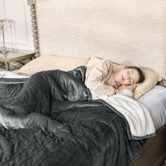 a woman laying on top of a bed under a blanket