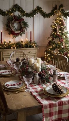 a dining room table set for christmas with pine cones, candles and plaid napkins