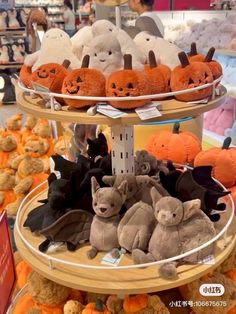 there are many stuffed animals on the three tiered trays with pumpkins in the background