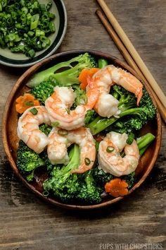 shrimp and broccoli served in a bowl with chopsticks on the side