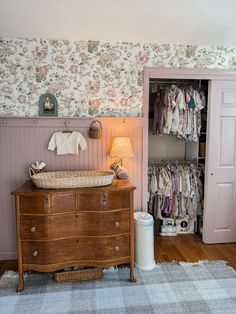 a baby's crib and dresser in a room with floral wallpaper