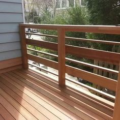 a wooden deck with railings and trees in the background