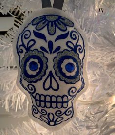 a blue and white sugar skull ornament hanging from a christmas tree