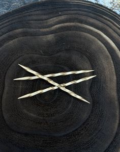 two pairs of scissors are stuck in the center of a black piece of wood that has been cut into smaller pieces