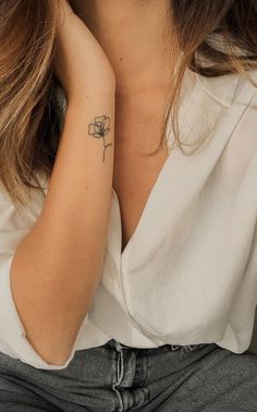 a woman with a small flower tattoo on her left arm and right arm behind her head