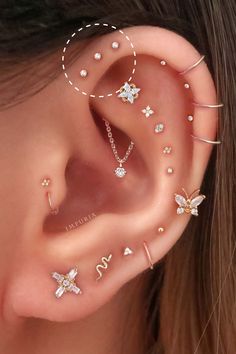 an ear with four different piercings on it, including two butterfly and one star