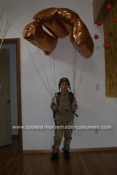 a young boy is holding some balloons in the shape of an army uniform and standing on a hard wood floor