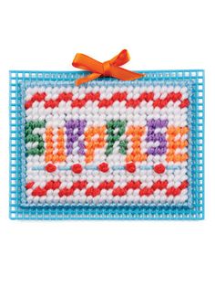 a cross stitch happy birthday sign with an orange bow