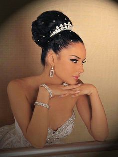 a woman wearing a tiara sitting in front of a mirror with her hand on her chin