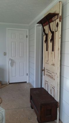 an open door with a bench in front of it next to a wall mounted coat rack