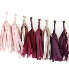 several tassels hanging on a wall in different shades of pink, red and purple