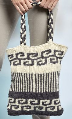 a woman is holding a knitted bag