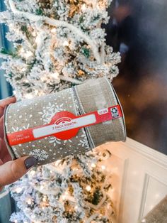 a person holding a roll of toilet paper in front of a christmas tree