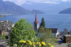 a church steeple in the middle of a town with water and mountains in the background