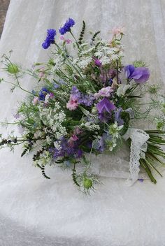 a bouquet of flowers sitting on top of a white cloth covered table next to a wall