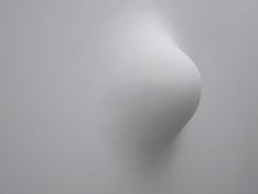 an abstract photo of a curved white object in the middle of foggy sky with light coming from behind it