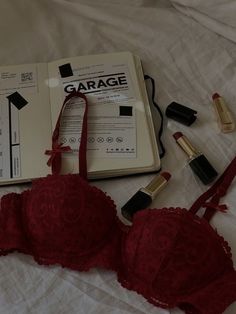 an open book, bra and lipstick on a bed