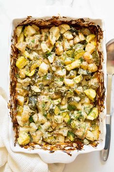 a casserole dish filled with potatoes and broccoli on a white table