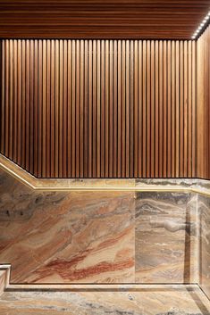 an empty room with wood paneling on the wall and marble floor in front of it