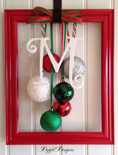 a red frame with ornaments hanging from it's sides and the letter m on top