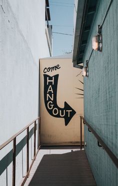 a sign that says hang out on the side of a building next to a stairway