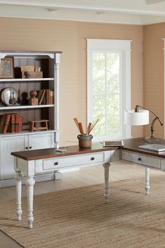 a home office with desk, bookshelf and lamp