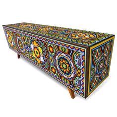 an ornately decorated chest with wooden legs and colorful designs on the front, against a white background