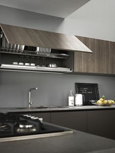 a modern kitchen with stainless steel appliances and wood cabinetry on the countertop, along with an oven hood