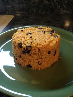 a piece of rice and raisins on a green plate with a black granite counter top