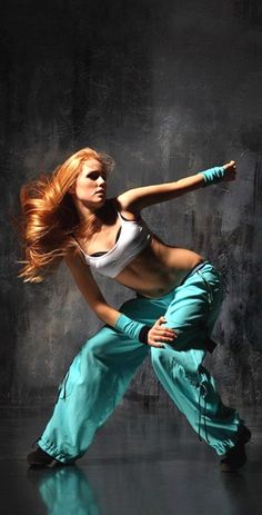 a woman with red hair is dancing on a black background and has her arms stretched out to the side