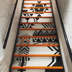 the stairs are painted with black and white geometric designs, along with orange handrails