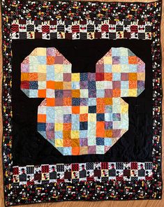 the mickey mouse quilt is made with many different colors and patterns on it's black backing