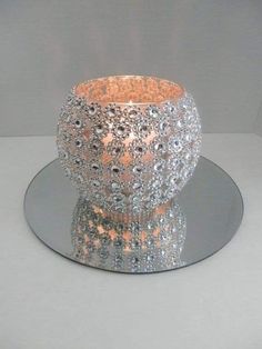 a glass candle holder sitting on top of a clear plate next to a white wall