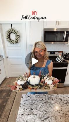 a woman standing in front of a kitchen counter with flowers and pumpkins on it