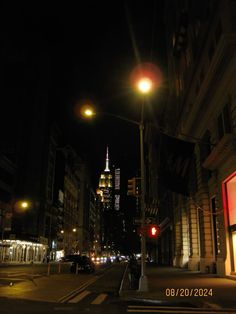 an empty city street at night with traffic lights and skyscrapers in the background,