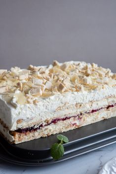 a cake with white frosting and toppings on a black platter next to a plate