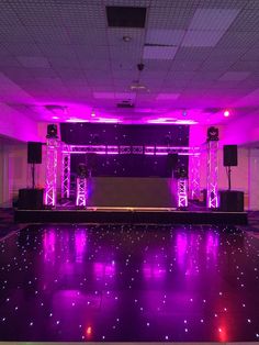 an empty dance floor is lit up with purple lights and sound speakers on the side