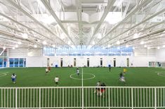 an indoor soccer field with people playing on the grass and in the middle of it