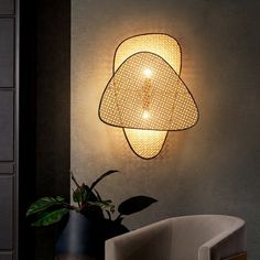 a light that is on the wall next to a chair and potted plant in front of it