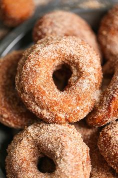 several sugared donuts piled on top of each other in a metal bowl with powdered sugar