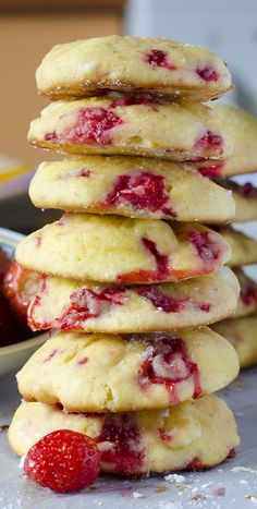 a stack of strawberry shortbread cookies next to a bowl of strawberries