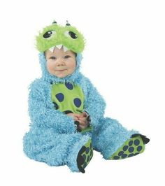 a baby dressed in a blue and green monster costume sitting on the ground with his legs crossed