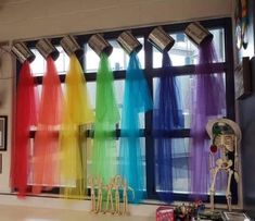 there are many different colored ribbons hanging on the window sill in front of the skeleton